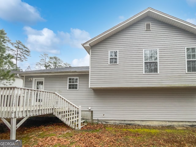 back of property featuring stairs and a deck