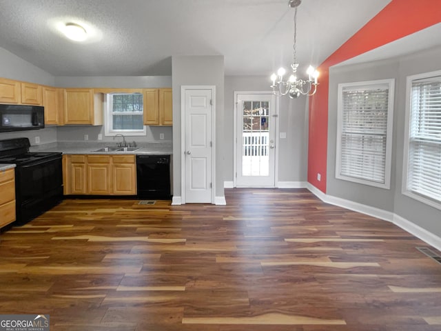 kitchen featuring vaulted ceiling, decorative light fixtures, a sink, and black appliances