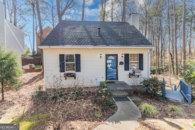 view of front facade featuring roof with shingles and a chimney