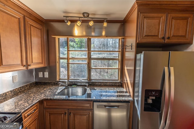 kitchen featuring appliances with stainless steel finishes, dark stone countertops, and brown cabinets