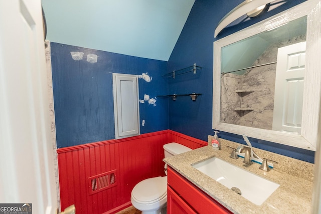 bathroom with lofted ceiling, visible vents, toilet, wainscoting, and vanity