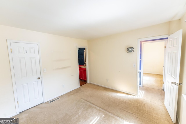 spare room with baseboards, visible vents, and light colored carpet