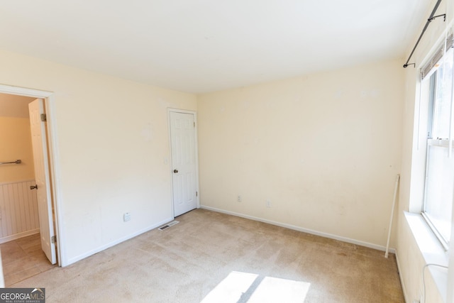 unfurnished bedroom with light carpet, visible vents, and ensuite bathroom