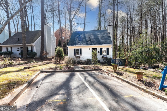 new england style home featuring a shingled roof and a chimney