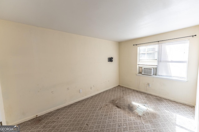 spare room with light carpet, baseboards, and cooling unit