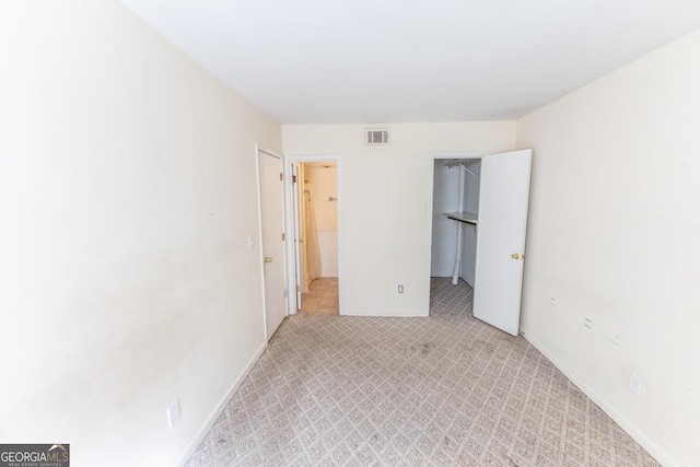 unfurnished bedroom with visible vents, a spacious closet, and baseboards