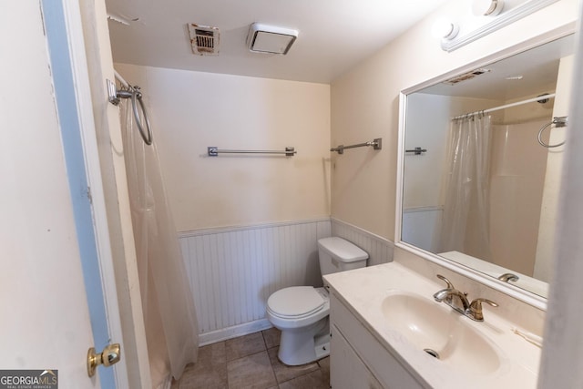 bathroom with a wainscoted wall, toilet, vanity, and visible vents