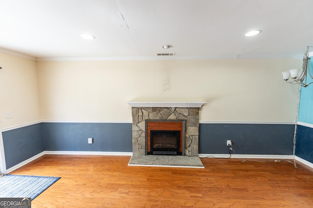 unfurnished living room with a fireplace, wood finished floors, visible vents, and crown molding