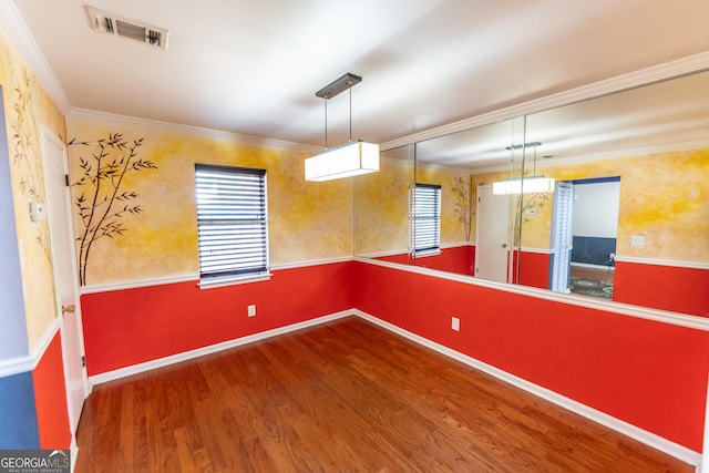 spare room featuring baseboards, crown molding, visible vents, and wood finished floors