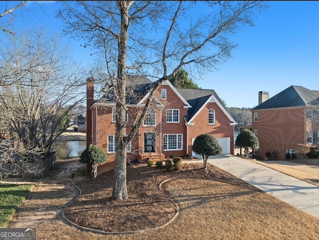 view of front of house featuring concrete driveway, brick siding, a chimney, and an attached garage