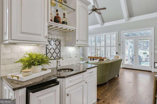 kitchen featuring dark wood finished floors, a ceiling fan, dark stone countertops, white cabinetry, and a sink