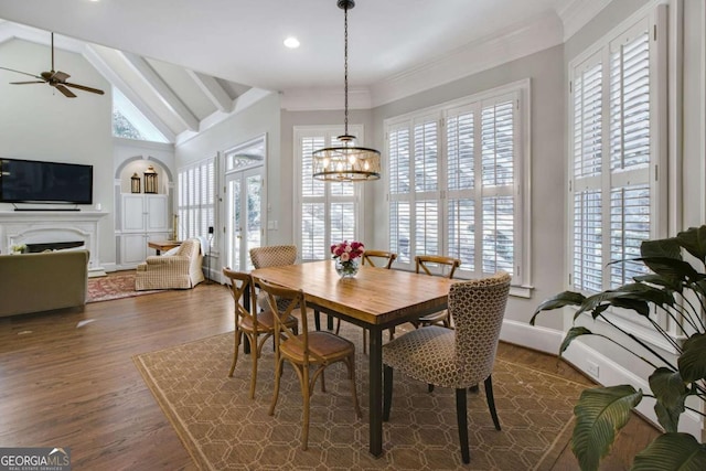 dining space with dark wood-style floors, crown molding, a fireplace, lofted ceiling with beams, and baseboards