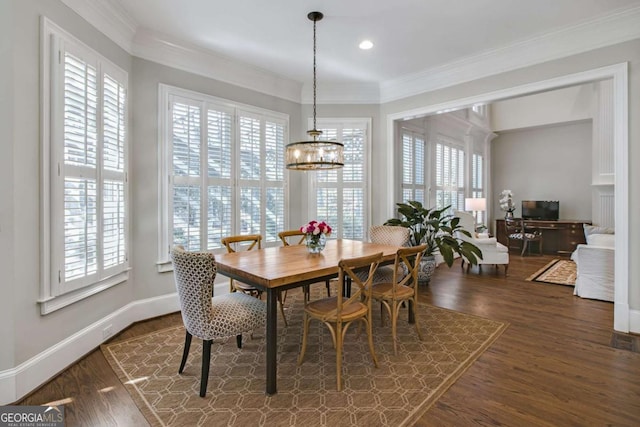 dining area with plenty of natural light, dark wood finished floors, a notable chandelier, and crown molding