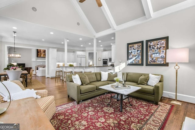 living area with baseboards, dark wood-type flooring, crown molding, high vaulted ceiling, and recessed lighting