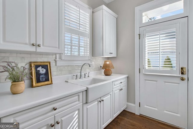 kitchen with a sink, white cabinetry, light countertops, and decorative backsplash