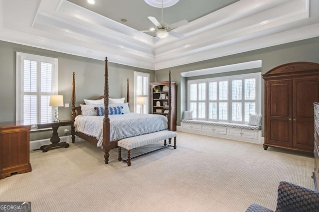 bedroom featuring light colored carpet, a tray ceiling, multiple windows, and crown molding