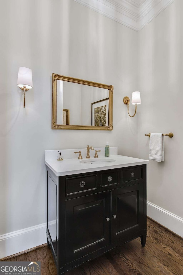 bathroom with baseboards, ornamental molding, wood finished floors, and vanity