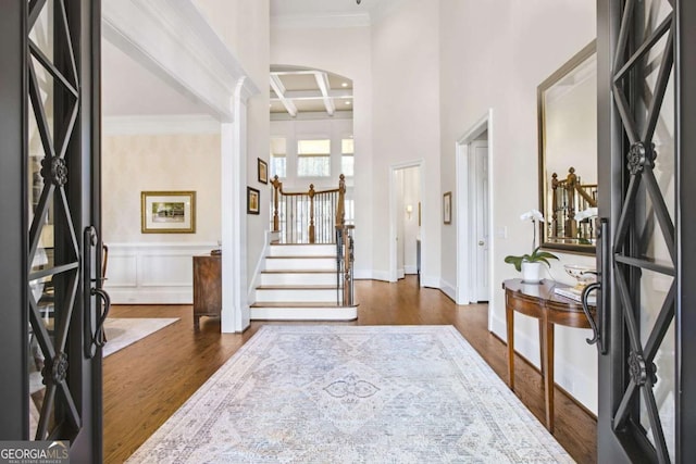 foyer entrance featuring coffered ceiling, ornamental molding, dark wood-style flooring, stairs, and beam ceiling