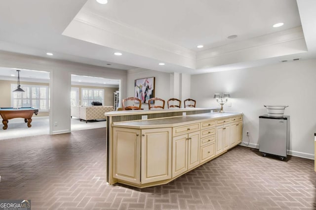 kitchen with light countertops, open floor plan, cream cabinetry, and a raised ceiling