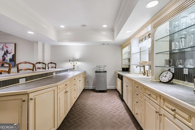 kitchen featuring brick floor, crown molding, cream cabinetry, a sink, and recessed lighting