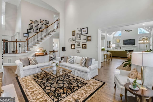 living area featuring light wood-style floors, visible vents, a fireplace, and a towering ceiling