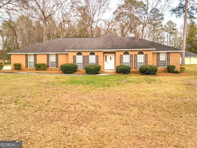 ranch-style house with brick siding, a chimney, and a front yard