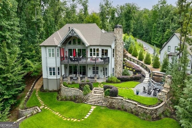 rear view of property featuring stairs, a lawn, and a patio area