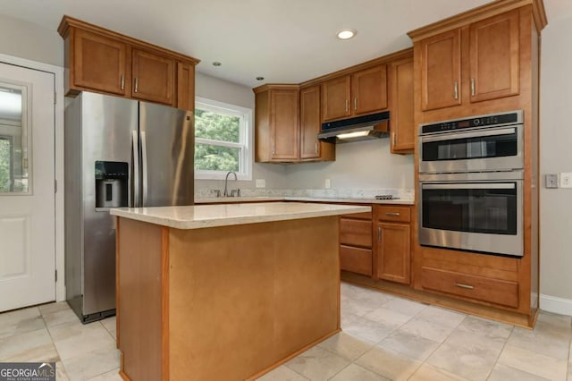 kitchen featuring under cabinet range hood, stainless steel appliances, light countertops, and brown cabinetry