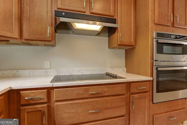 kitchen featuring stainless steel double oven, black electric cooktop, under cabinet range hood, light countertops, and brown cabinets