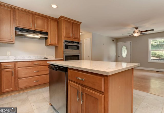 kitchen with stainless steel appliances, a center island, brown cabinets, and under cabinet range hood