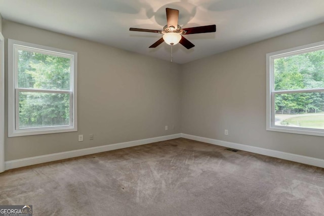 spare room featuring light carpet, ceiling fan, visible vents, and baseboards