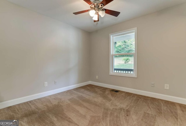 carpeted spare room featuring a ceiling fan, visible vents, and baseboards