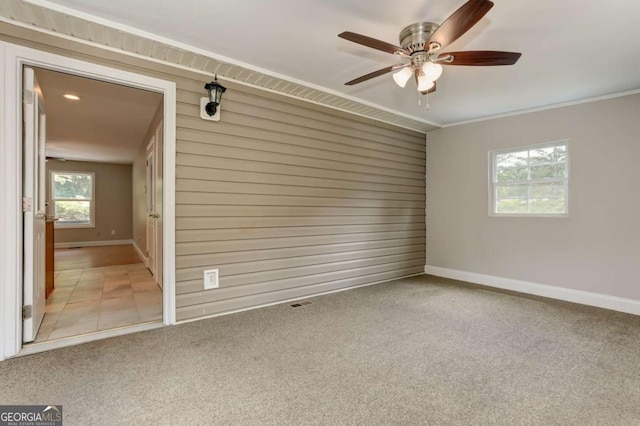 spare room with baseboards, crown molding, and light colored carpet