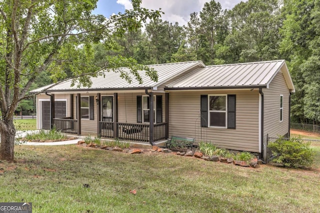 single story home with a garage, metal roof, a front lawn, and a porch