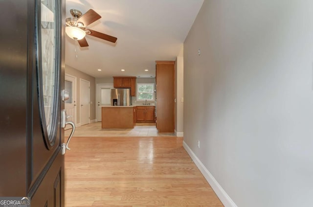 kitchen featuring light countertops, brown cabinetry, stainless steel fridge, and light wood-style floors