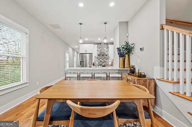 dining room with a healthy amount of sunlight, light wood-style flooring, baseboards, and recessed lighting