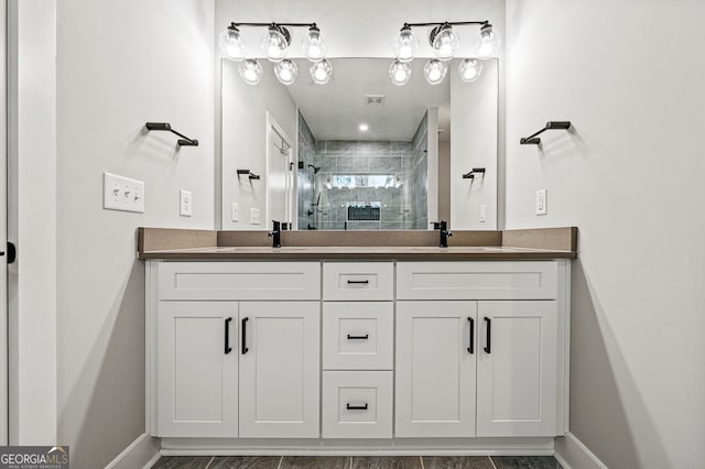 bathroom featuring double vanity, a shower stall, baseboards, and a sink