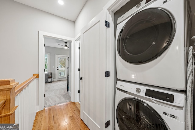 laundry area featuring recessed lighting, stacked washer and clothes dryer, light wood finished floors, and laundry area