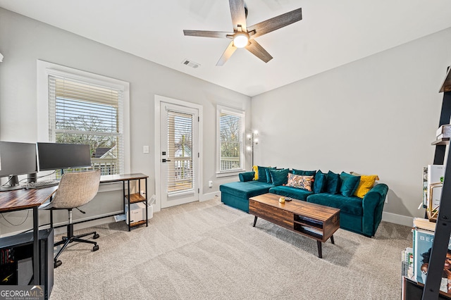 office area featuring baseboards, ceiling fan, visible vents, and light colored carpet