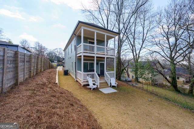 view of front of house with a front yard, a fenced backyard, a balcony, and central AC unit