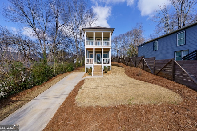 view of front of home featuring a porch, stairway, fence, and a balcony