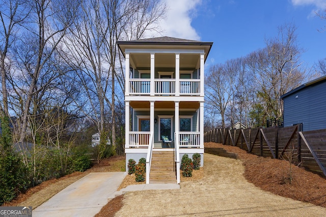 view of front of home featuring a balcony, stairs, fence, and a porch