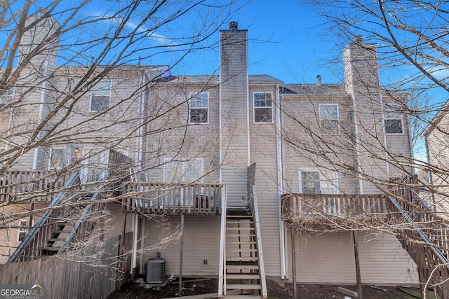 rear view of property with a balcony, a chimney, stairway, and cooling unit