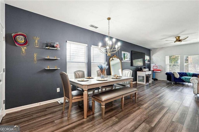 dining area with dark wood-type flooring, visible vents, baseboards, and ceiling fan with notable chandelier