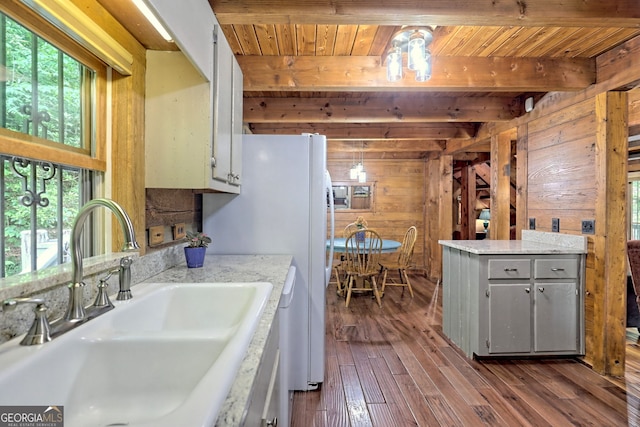 kitchen featuring dark wood-style flooring, a sink, light countertops, wood walls, and beam ceiling