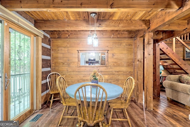 dining area with visible vents, beamed ceiling, hardwood / wood-style flooring, and wooden walls