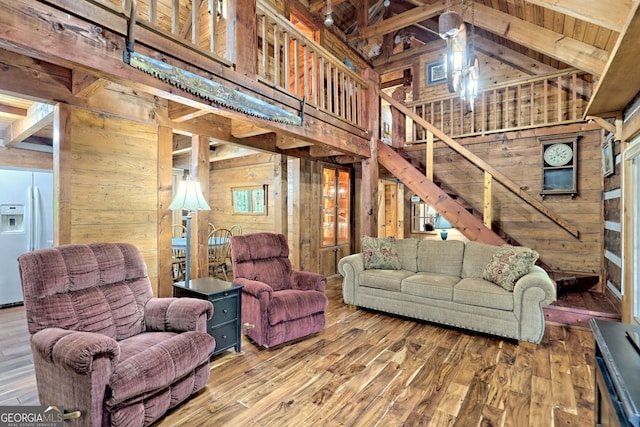 living area with wood walls, stairway, and wood finished floors