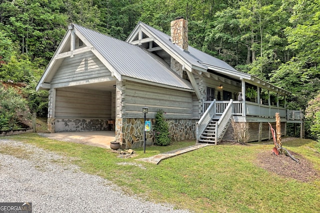 view of front of home with metal roof, driveway, stairway, a chimney, and a front yard