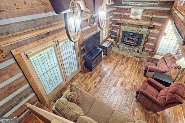 living room featuring a wood stove, wooden walls, and wood finished floors