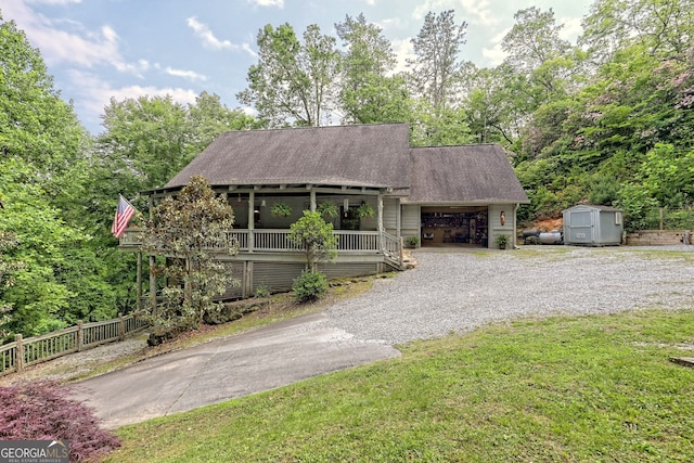 view of front of house with gravel driveway, a storage shed, fence, a garage, and an outdoor structure